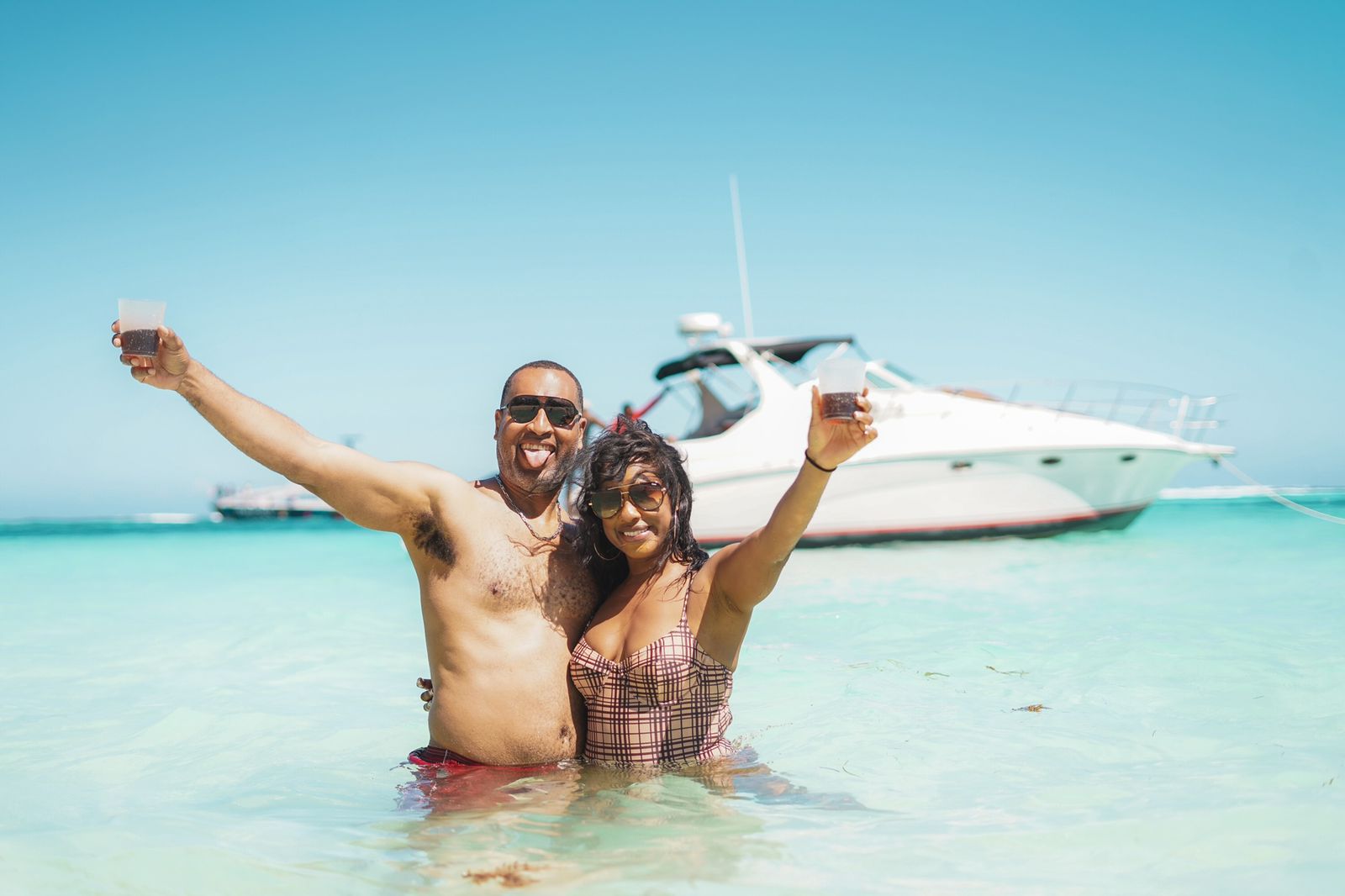Happy couple celebrating in the water in front of a yacht in Punta Cana